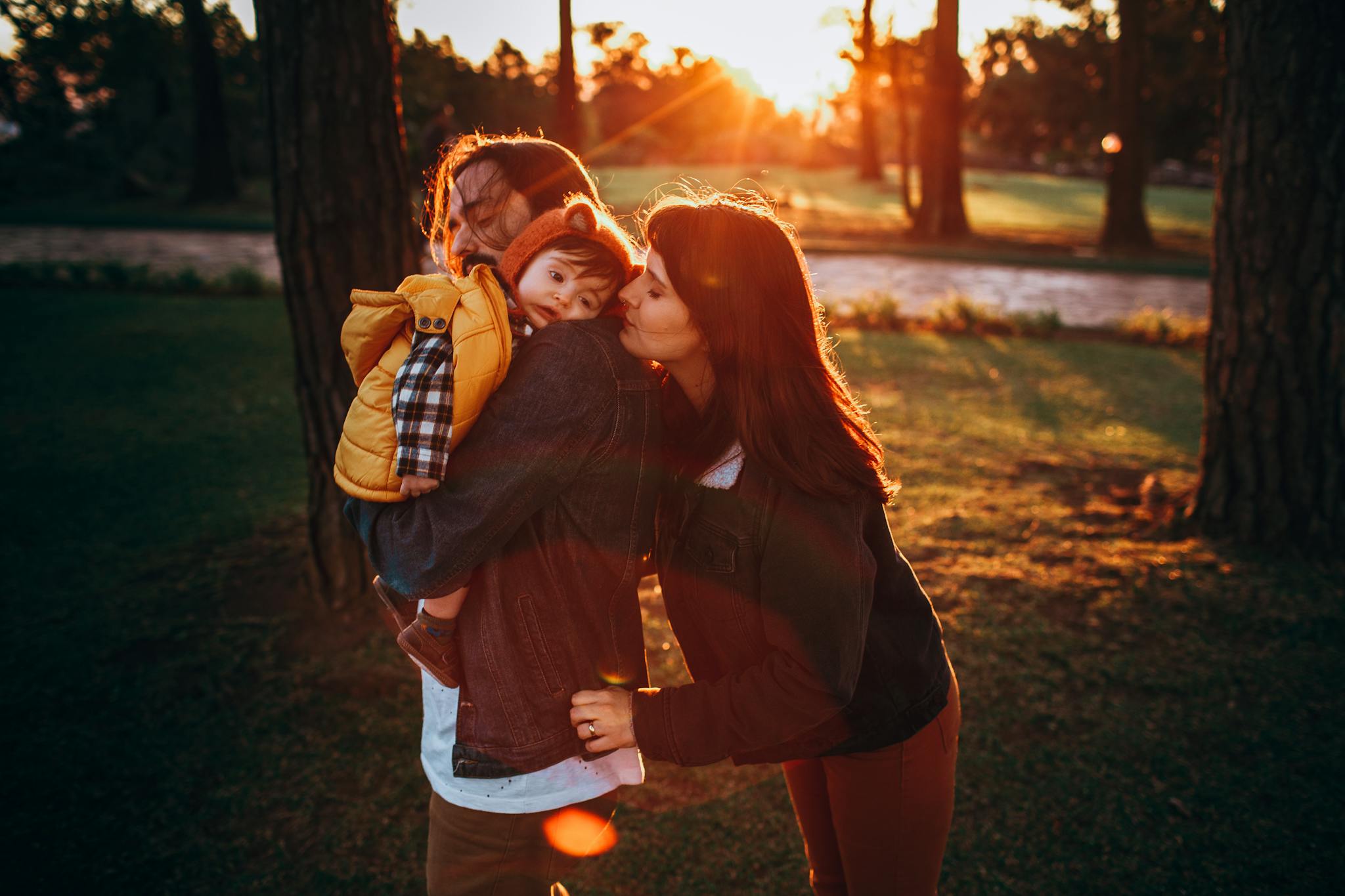 A loving family shares a warm moment outdoors at sunset, highlighting affection and closeness.